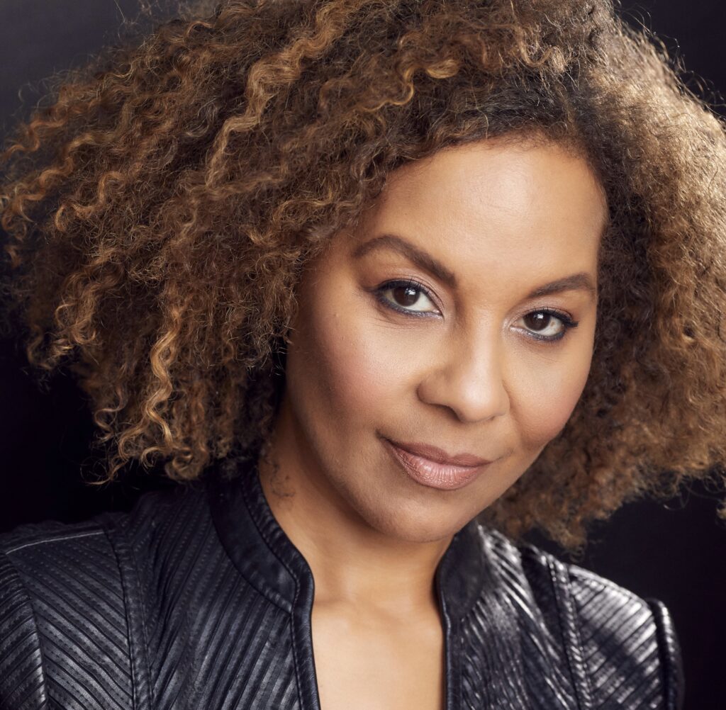 A woman with curly hair wearing black leather jacket.