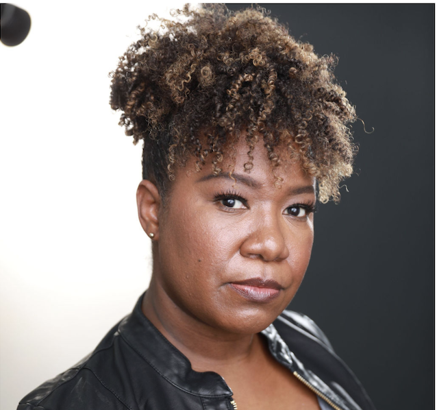 A woman with curly hair and black jacket.