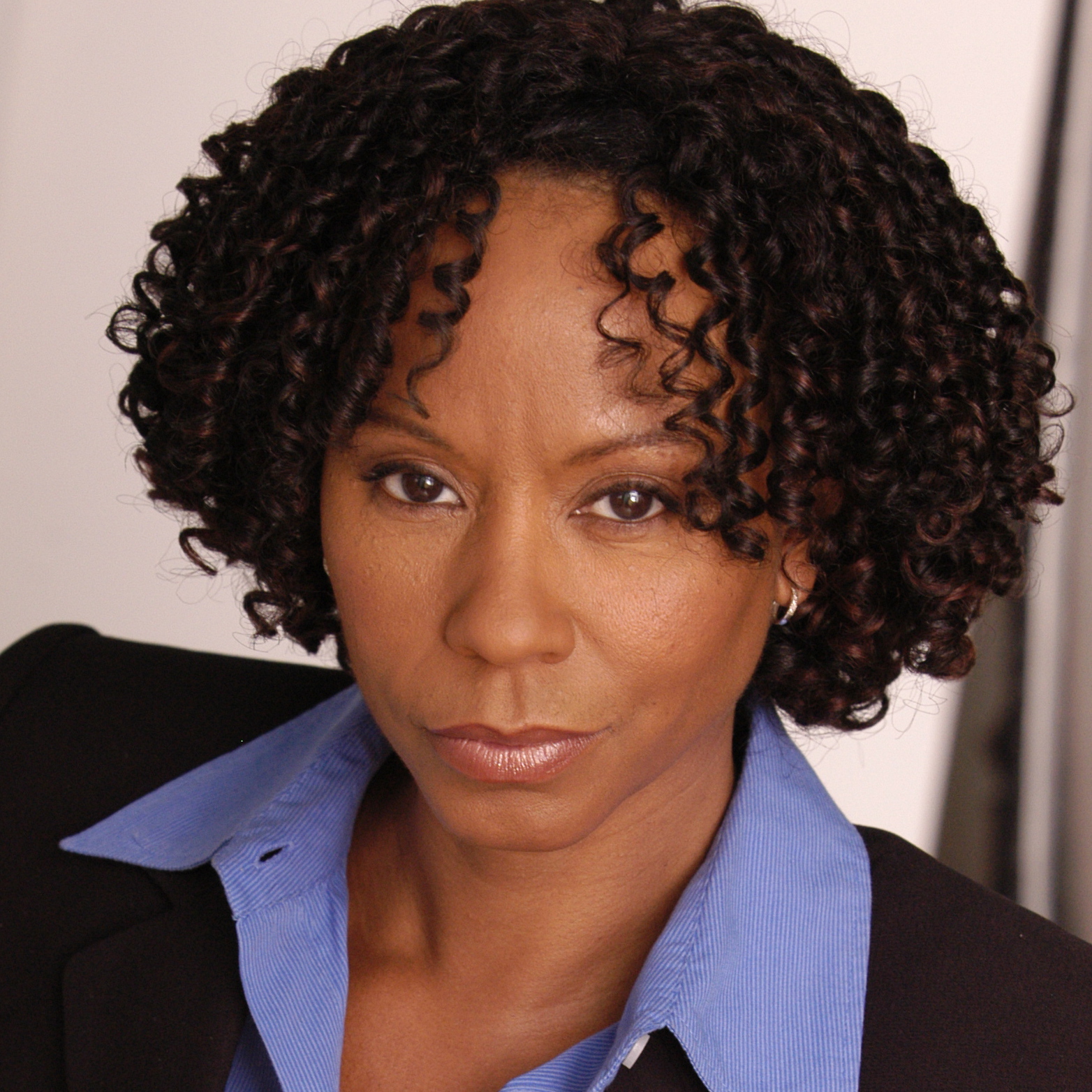 A woman with curly hair wearing a blue shirt.