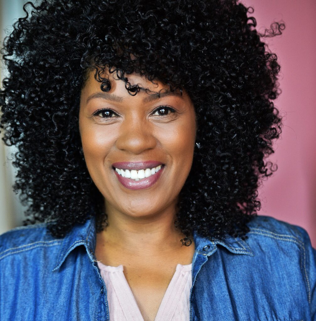 A woman with curly hair smiling for the camera.