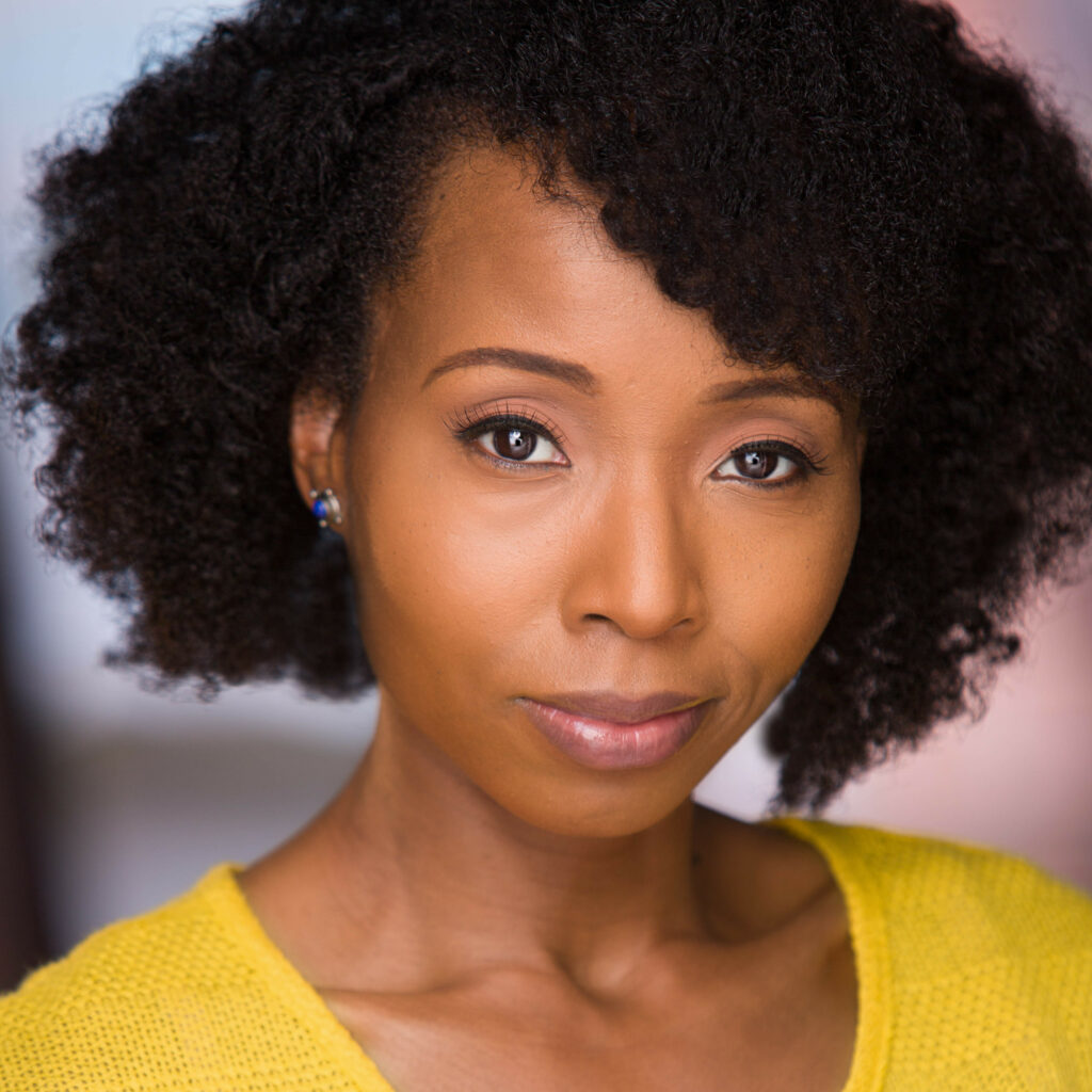 A woman with curly hair wearing a yellow shirt.