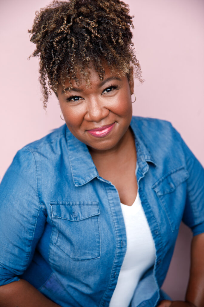 A woman with curly hair wearing a blue shirt.