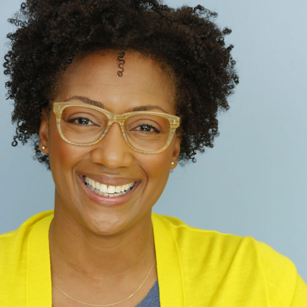 A woman with glasses and a yellow jacket