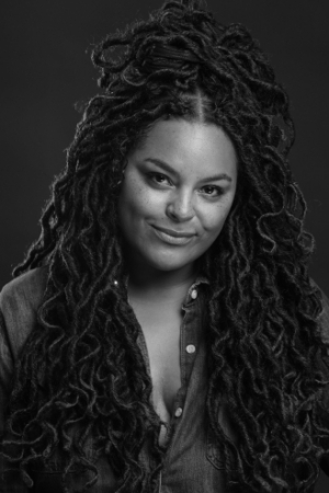 A woman with long dreadlocks wearing a button up shirt.