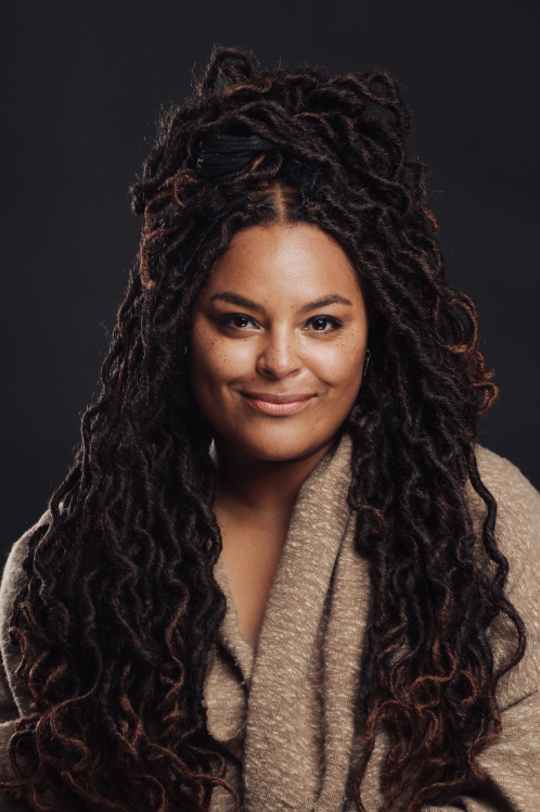 A woman with long dreadlocks wearing a sweater.