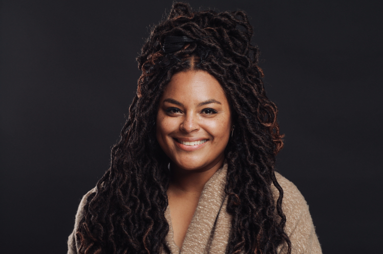 A woman with long dreadlocks wearing a sweater.