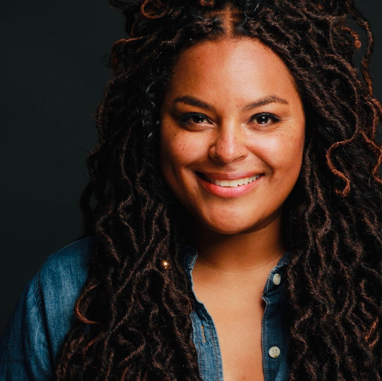 A woman with long dreadlocks wearing a blue shirt.