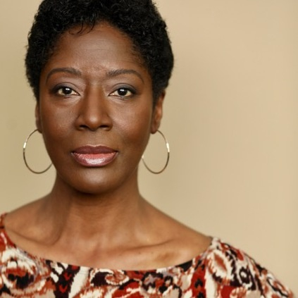 A woman with short hair wearing a floral shirt.