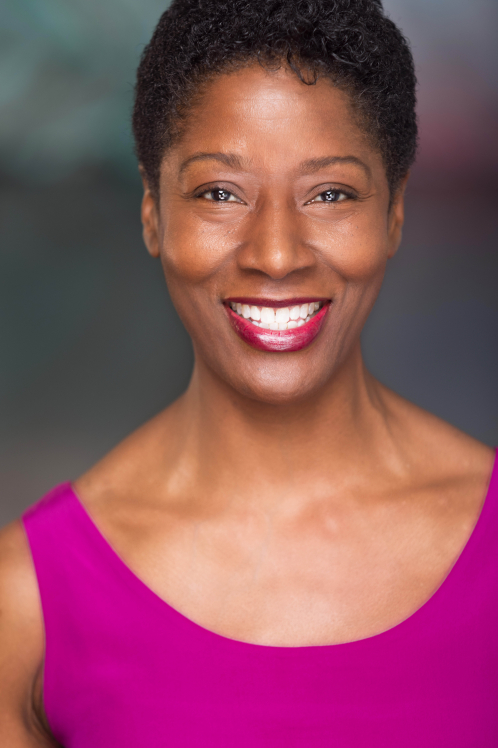 A woman in a pink top smiling for the camera.