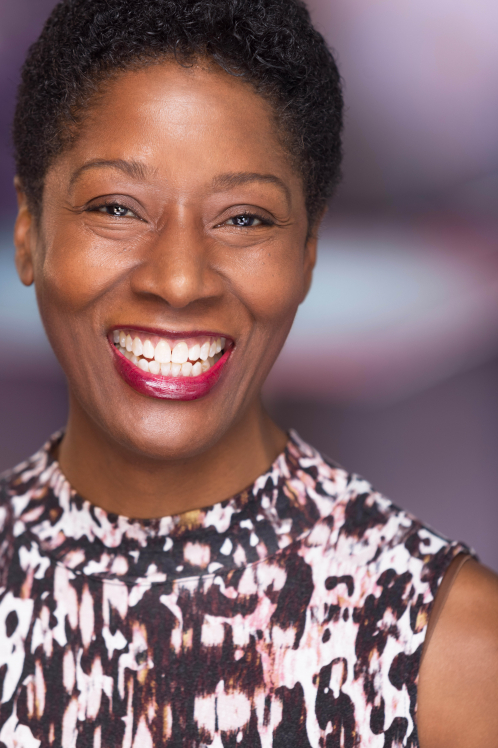 A woman with brown hair and pink lipstick smiles.